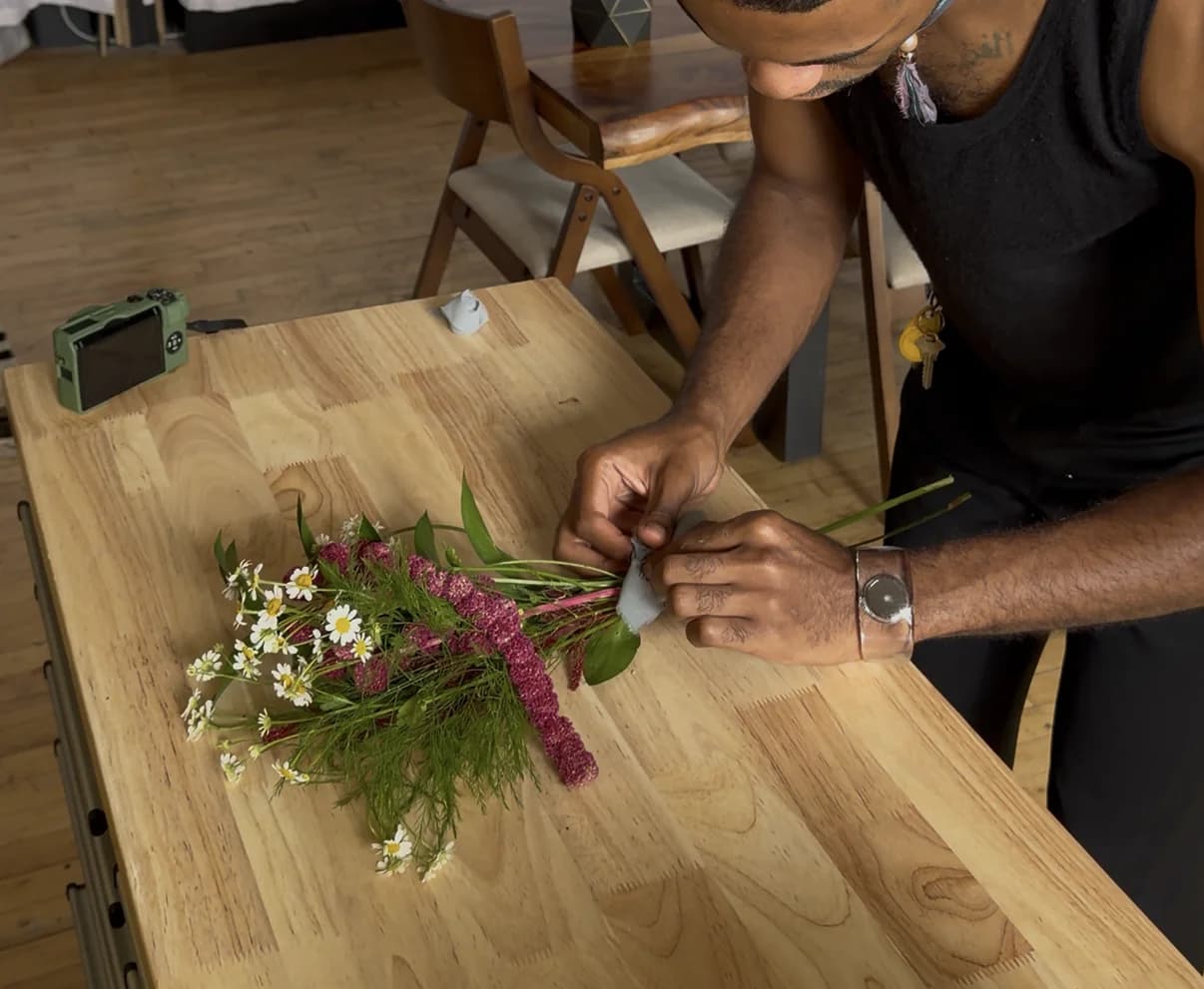 Flowers are gathered and bound into an arrangement as the shared table is deconstructed.
